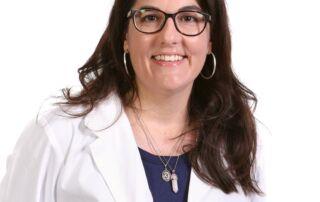 Smiling woman in a white lab coat and glasses, professional portrait.